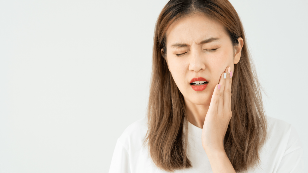 Muelas del juicio: Cuándo es realmente necesario sacarlas (y cuándo no) 3 Primer plano de perfil de una persona sosteniendo una muela del juicio recién extraída entre los dedos y señalando con la otra mano la zona de su mandíbula en Tetuán, Madrid.